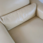 Fauteuil club vintage en cuir beige des années 80 avec accoudoirs larges et assise enveloppante.