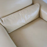 Fauteuil club vintage en cuir beige des années 80 avec accoudoirs larges et assise enveloppante.