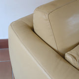Fauteuil club vintage en cuir beige des années 80 avec accoudoirs larges et assise enveloppante.