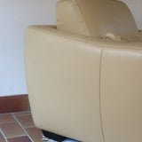Fauteuil club vintage en cuir beige des années 80 avec accoudoirs larges et assise enveloppante.
