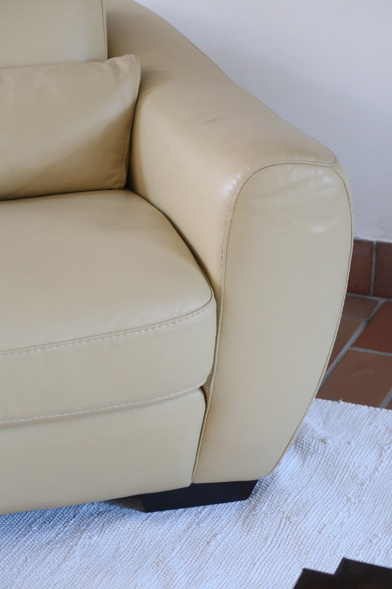 Fauteuil club vintage en cuir beige des années 80 avec accoudoirs larges et assise enveloppante.