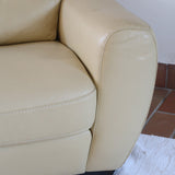Fauteuil club vintage en cuir beige des années 80 avec accoudoirs larges et assise enveloppante.