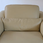 Fauteuil club vintage en cuir beige des années 80 avec accoudoirs larges et assise enveloppante.