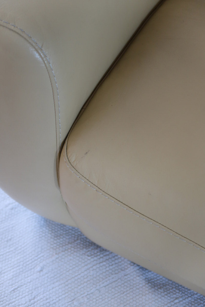 Fauteuil club vintage en cuir beige des années 80 avec accoudoirs larges et assise enveloppante.