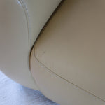 Fauteuil club vintage en cuir beige des années 80 avec accoudoirs larges et assise enveloppante.