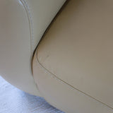 Fauteuil club vintage en cuir beige des années 80 avec accoudoirs larges et assise enveloppante.