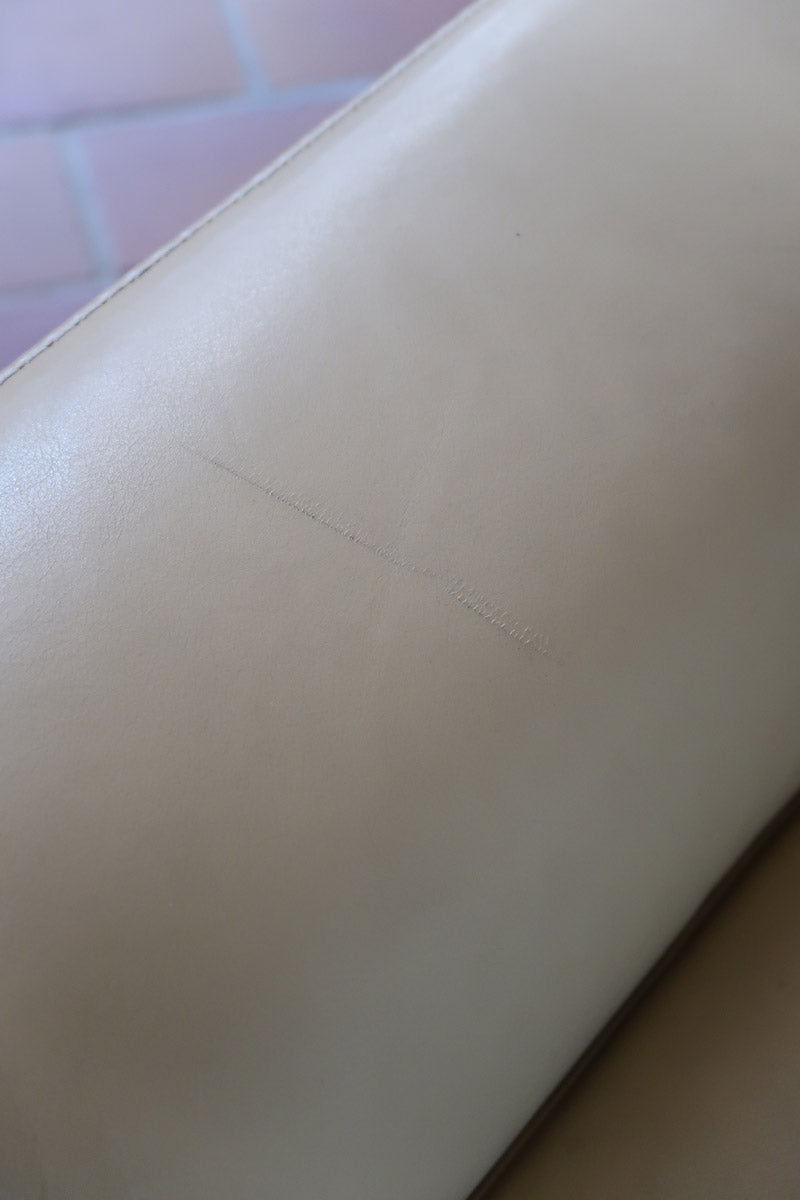 Fauteuil club vintage en cuir beige des années 80 avec accoudoirs larges et assise enveloppante.