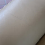 Fauteuil club vintage en cuir beige des années 80 avec accoudoirs larges et assise enveloppante.