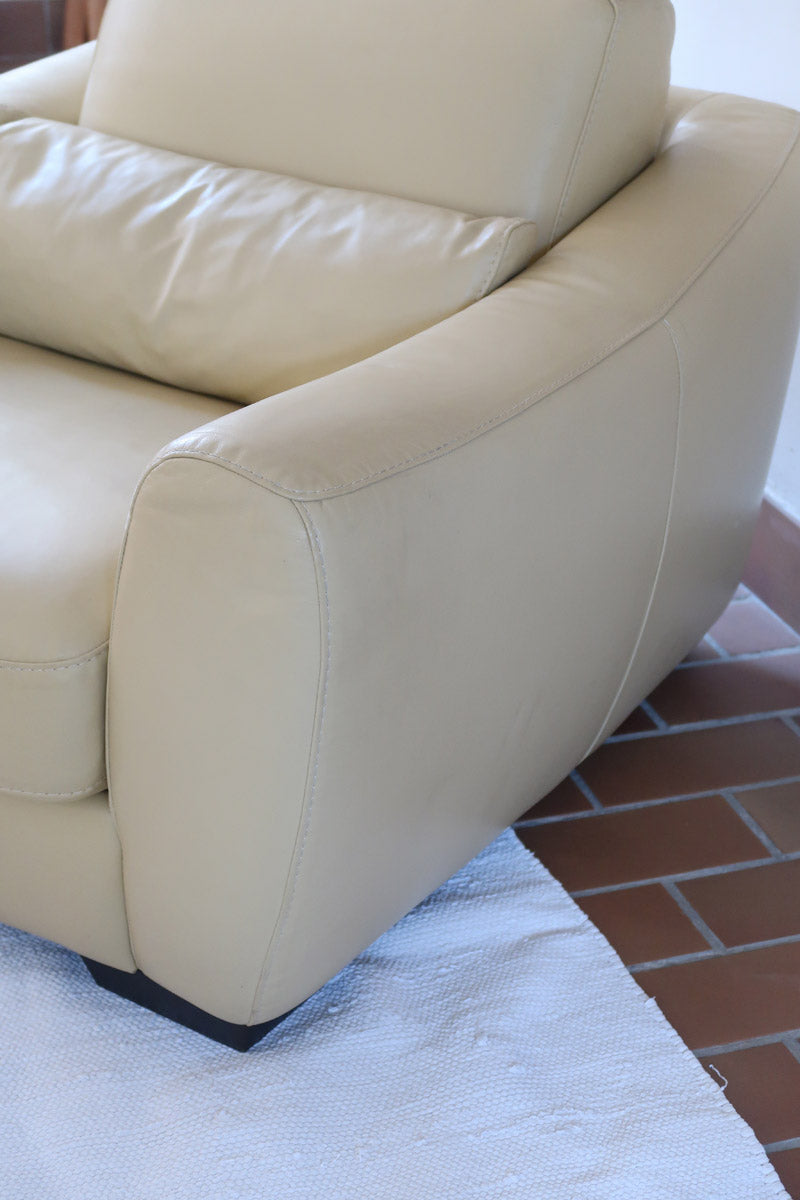 Fauteuil club vintage en cuir beige des années 80 avec accoudoirs larges et assise enveloppante.