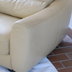 Fauteuil club vintage en cuir beige des années 80 avec accoudoirs larges et assise enveloppante.