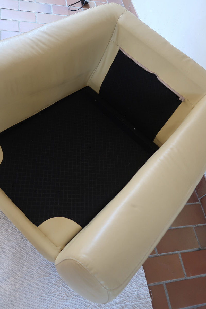 Fauteuil club vintage en cuir beige des années 80 avec accoudoirs larges et assise enveloppante.