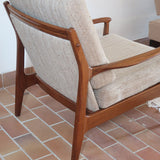 Fauteuil lounge scandinave vintage en teck années 60, accoudoirs effilés, dossier inclinable, coussins tissu chiné écru, esprit Komfort