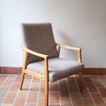 Fauteuil scandinave années 60 en bois clair avec assise retapissée tissu brun, accoudoirs galbés.