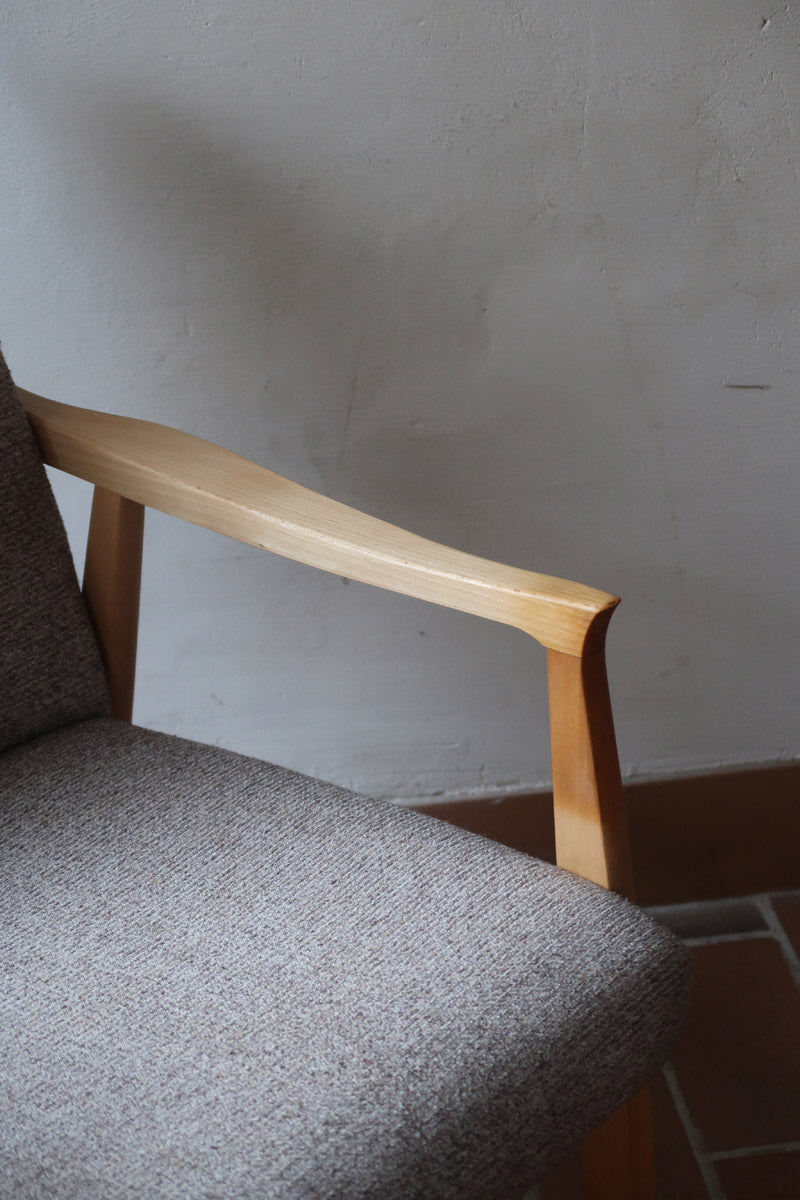 Fauteuil scandinave années 60 en bois clair avec assise retapissée tissu brun, accoudoirs galbés.