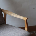 Fauteuil scandinave années 60 en bois clair avec assise retapissée tissu brun, accoudoirs galbés.