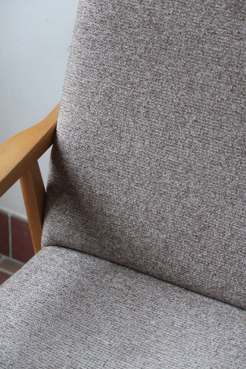 Fauteuil scandinave années 60 en bois clair avec assise retapissée tissu brun, accoudoirs galbés.