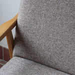 Fauteuil scandinave années 60 en bois clair avec assise retapissée tissu brun, accoudoirs galbés.
