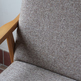 Fauteuil scandinave années 60 en bois clair avec assise retapissée tissu brun, accoudoirs galbés.