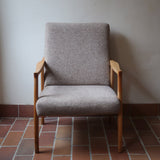 Fauteuil scandinave années 60 en bois clair avec assise retapissée tissu brun, accoudoirs galbés.
