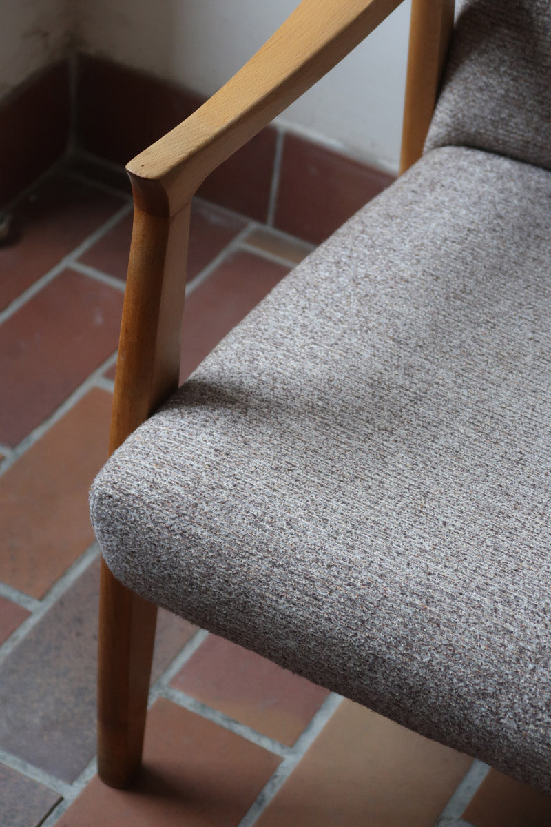 Fauteuil scandinave années 60 en bois clair avec assise retapissée tissu brun, accoudoirs galbés.