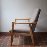 Fauteuil scandinave années 60 en bois clair avec assise retapissée tissu brun, accoudoirs galbés.