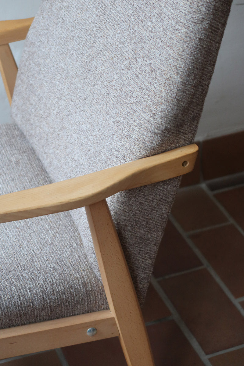 Fauteuil scandinave années 60 en bois clair avec assise retapissée tissu brun, accoudoirs galbés.