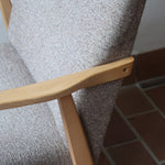 Fauteuil scandinave années 60 en bois clair avec assise retapissée tissu brun, accoudoirs galbés.