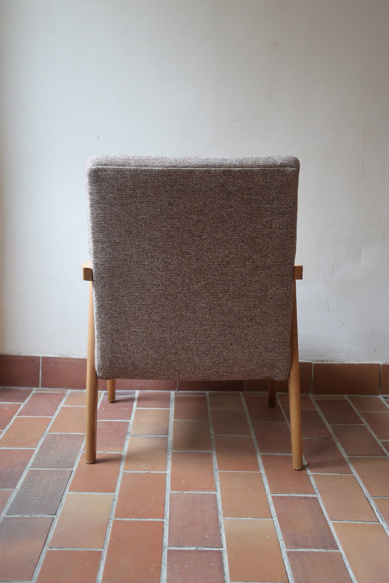 Fauteuil scandinave années 60 en bois clair avec assise retapissée tissu brun, accoudoirs galbés.