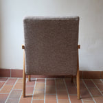 Fauteuil scandinave années 60 en bois clair avec assise retapissée tissu brun, accoudoirs galbés.