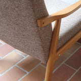 Fauteuil scandinave années 60 en bois clair avec assise retapissée tissu brun, accoudoirs galbés.