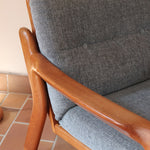 Fauteuil scandinave en teck Komfor avec coussins bleu gris déhoussables et piètement luge, fabriqué au Danemark.