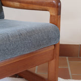 Fauteuil scandinave en teck Komfor avec coussins bleu gris déhoussables et piètement luge, fabriqué au Danemark.