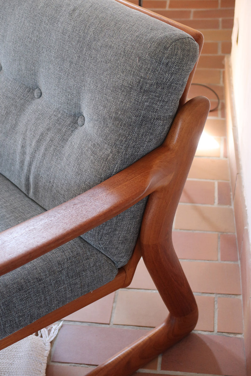 Fauteuil scandinave en teck Komfor avec coussins bleu gris déhoussables et piètement luge, fabriqué au Danemark.