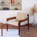 Fauteuil scandinave en teck des années 60 avec coussins beige et dossier à barreaux.