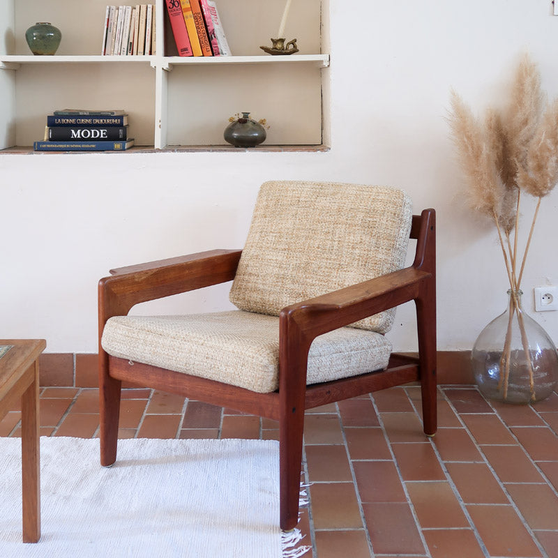 Fauteuil scandinave en teck des années 60 avec coussins beige et dossier à barreaux.