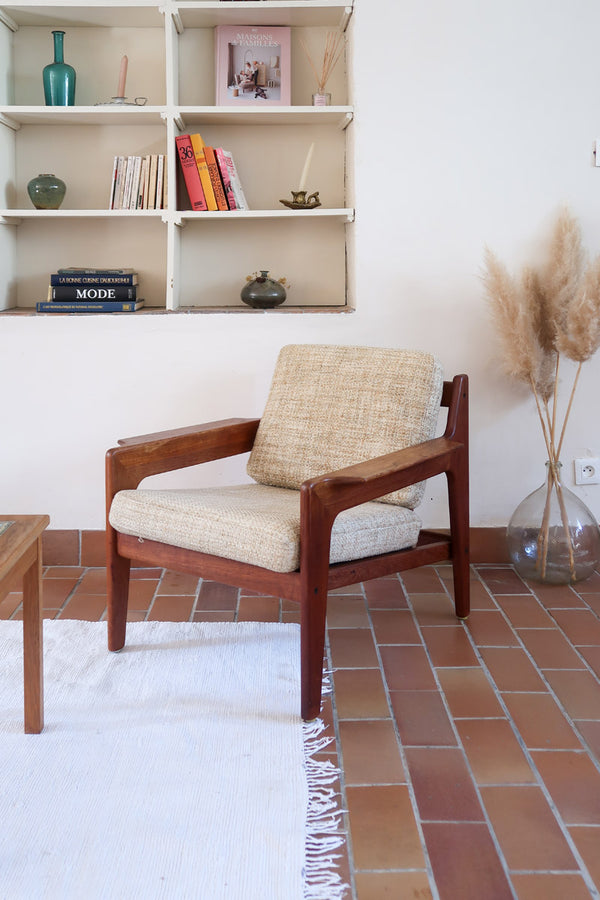 Fauteuil scandinave en teck des années 60 avec coussins beige et dossier à barreaux.