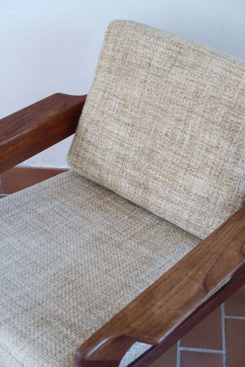 Fauteuil scandinave en teck des années 60 avec coussins beige et dossier à barreaux.