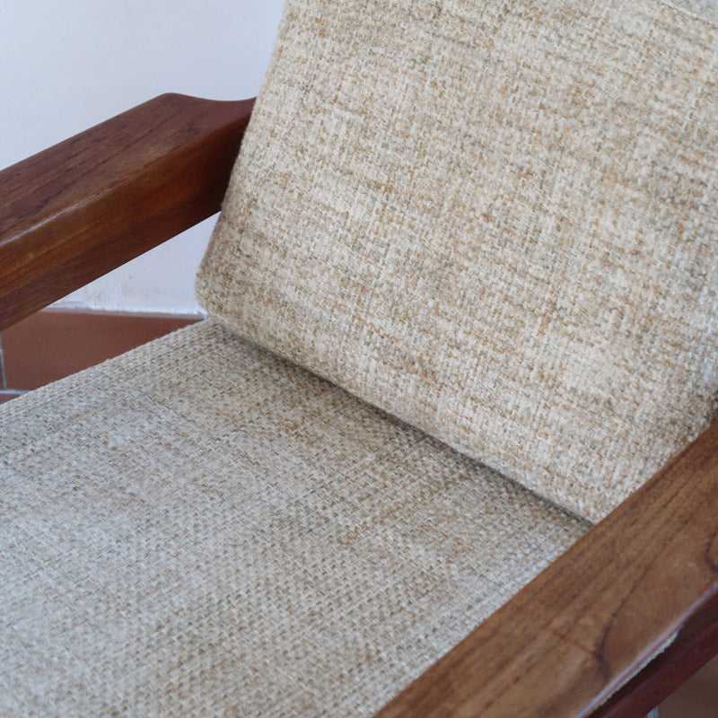 Fauteuil scandinave en teck des années 60 avec coussins beige et dossier à barreaux.
