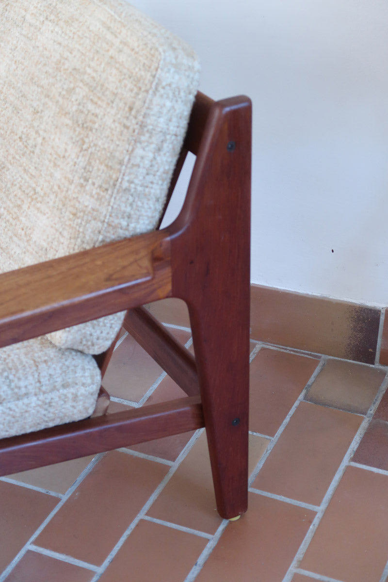 Fauteuil scandinave en teck des années 60 avec coussins beige et dossier à barreaux.