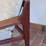 Fauteuil scandinave en teck des années 60 avec coussins beige et dossier à barreaux.