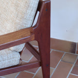 Fauteuil scandinave en teck des années 60 avec coussins beige et dossier à barreaux.