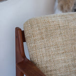Fauteuil scandinave en teck des années 60 avec coussins beige et dossier à barreaux.