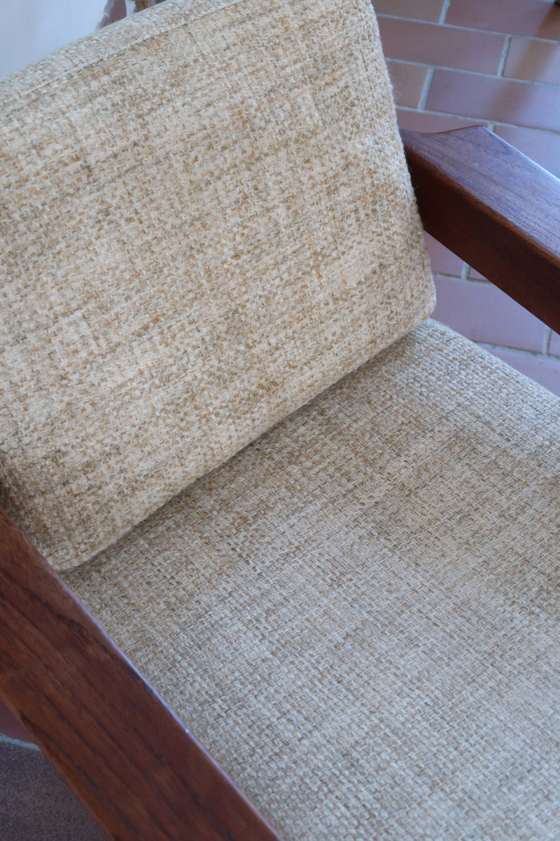 Fauteuil scandinave en teck des années 60 avec coussins beige et dossier à barreaux.