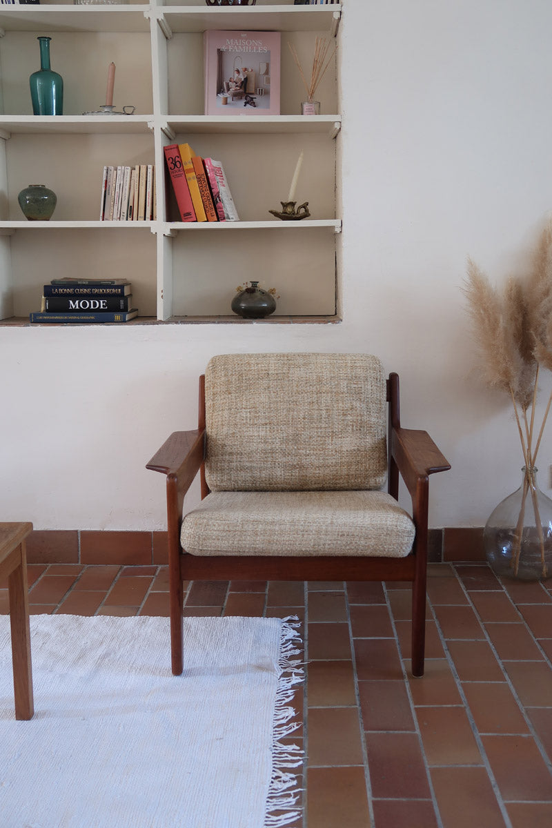 Fauteuil scandinave en teck des années 60 avec coussins beige et dossier à barreaux.