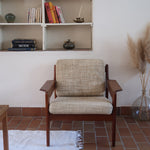 Fauteuil scandinave en teck des années 60 avec coussins beige et dossier à barreaux.