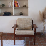 Fauteuil scandinave en teck des années 60 avec coussins beige et dossier à barreaux.