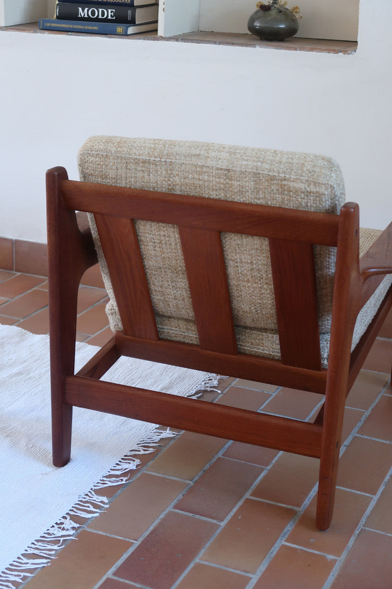 Fauteuil scandinave en teck des années 60 avec coussins beige et dossier à barreaux.
