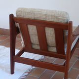 Fauteuil scandinave en teck des années 60 avec coussins beige et dossier à barreaux.