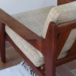 Fauteuil scandinave en teck des années 60 avec coussins beige et dossier à barreaux.