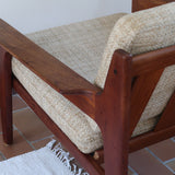 Fauteuil scandinave en teck des années 60 avec coussins beige et dossier à barreaux.